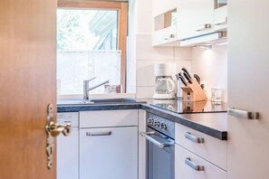A modern kitchen with a built-in dishwasher, a coffee maker, and a knife block on the countertop. - Farmhouse by the sea || Langballig (Langballig)