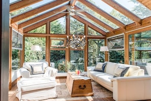 A sunlit room with a sloped ceiling, wooden beams, and large windows. - Farmhouse by the sea || Langballig (Langballig)