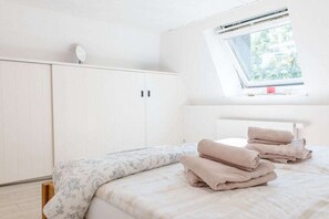 Un dormitorio con una cama, una ventana y un armario.