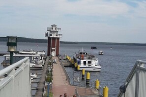 Eine Pier mit vertäuten Booten, einem Leuchtturm und freiem Blick auf das Wasser.