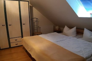 Ein Schlafzimmer mit einem Bett, einem Kleiderschrank, einer Heizung und einem Oberlicht.