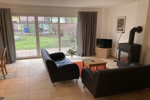 A living room with a sofa, a television, a fireplace, and a view through a glass door. - Holiday home with 3 bedrooms (Ostseebad Prerow)