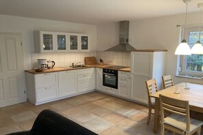 A kitchen with white cabinets, a wooden countertop, an oven, and a dining table with chairs. - Holiday home with 3 bedrooms (Ostseebad Prerow)