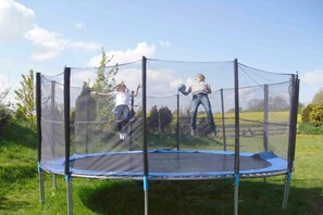 A trampoline with a safety net enclosure in a grassy outdoor area. - Holiday apartment with 2 bedrooms (Stoltebüll)