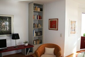 A living room with a bookshelf, a television, a lamp, and a chair. - Holiday apartment with sea view, Villa Vineta 14 (Seebad Bansin)