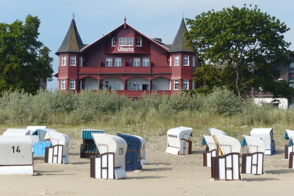 A large red building with the name 'Vineta' on the facade, surrounded by beach huts.