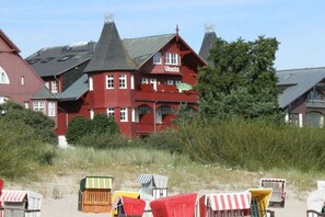 A red building with the name 'Vineta' on the facade, surrounded by beach chairs and vegetation. - Holiday apartment with sea view, Villa Vineta 14 (Seebad Bansin)