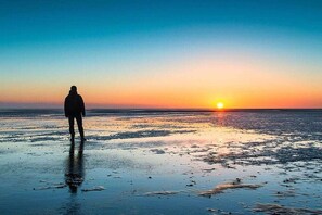 A person standing on a beach at sunset. - Holiday apartment BLAUORT in the home by the sea (Büsum)
