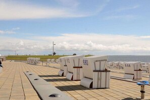A deck with rows of numbered seating areas, a clear sky, and a distant view of the sea. - Holiday apartment BLAUORT in the home by the sea (Büsum)