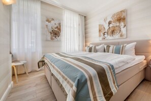 Ein Schlafzimmer mit einem großen Bett, einem Nachttisch und zwei an der Wand befestigten Kunstwerken.