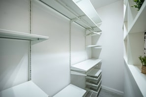 Ein helles, weißes Interieur mit eingebauten Regalen und einer Zimmerpflanze rechts.