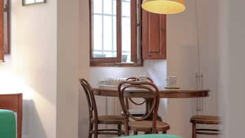 Un comedor con mesa de madera, cuatro sillas y una lámpara colgante.