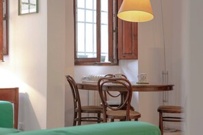 Un comedor con mesa de madera, cuatro sillas y una lámpara colgante.