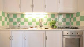 A kitchen with white cabinets, a sink, a stove, and a tiled backsplash.
