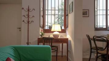 A room with a green sofa, a wooden desk with a lamp, a chair, and a radiator.