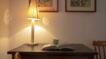 A wooden desk with a lamp, an open book, and a striped mug.