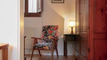 A chair with floral upholstery, a wooden cabinet, and a table with a lamp.