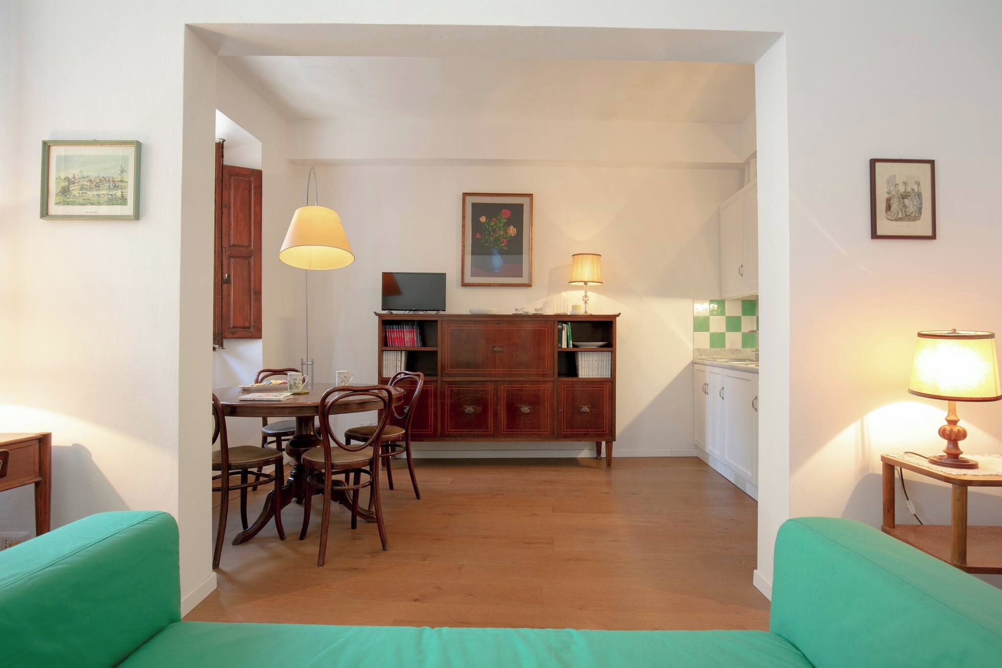 A compact living space with a dining area, kitchenette, and a green sofa.