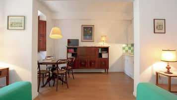 A compact living space with a dining area, kitchenette, and a green sofa.