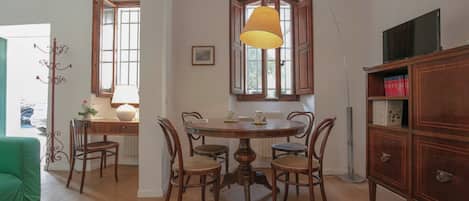 A dining area with a round wooden table, four chairs, a lamp, and a bookshelf.