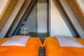 Ein Zimmer mit zwei Betten, einem kleinen Tisch und einer Tür zu einem anderen Raum.