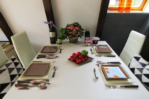 A dining table set for four with plates, cutlery, and a centerpiece of red berries and a flower. - Holiday home with 1 bedroom (Hollern-Twielenfleth)