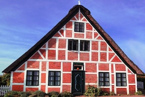 A red brick building with white trim and a black door. - Holiday home with 1 bedroom (Hollern-Twielenfleth)