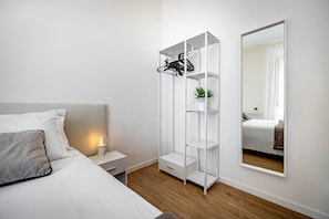 A bedroom with a bed, bedside table, nightstand, white wardrobe, and a full-length mirror. - Aleardi (Florence)