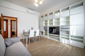 A modern living room with a sofa, dining table, chairs, and built-in shelving units. - Aleardi (Florence)