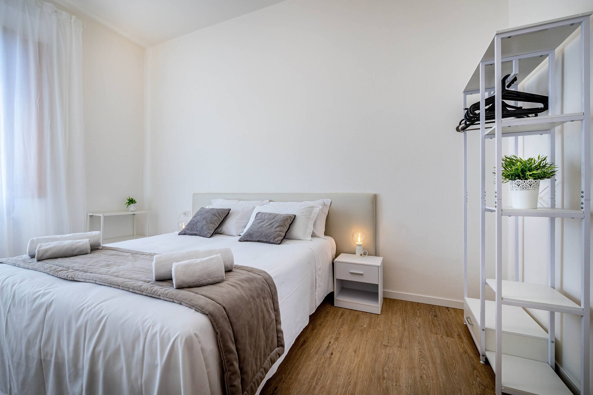 Un dormitorio moderno con cama, mesitas de noche, un armario y una planta en maceta.