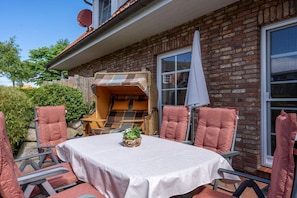 Eine Terrassensitzgruppe im Freien mit Tisch und Stühlen aus Rattan, ausgestattet mit Kissen.