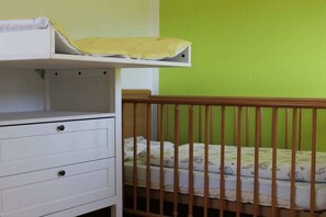 A crib with a wooden frame and a mattress with a patterned sheet. - North Sea holiday Stormhus (Sankt Peter-Ording)