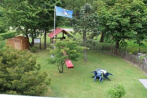 A fenced backyard with a slide, a small wooden structure, and a flag. - North Sea holiday Stormhus (Sankt Peter-Ording)