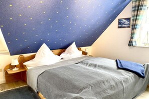 Ein Schlafzimmer mit einem Bett, Kissen, einem Nachttisch, einer Lampe und einer von Sternen verzierten Decke.