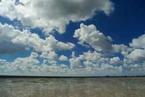 Ein Strand mit blauem Himmel und vereinzelten Wolken.