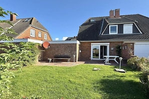 Ein Wohnhaus mit Ziegelhaus, überdachter Terrasse, Satellitenschüssel und kleinem Garten.