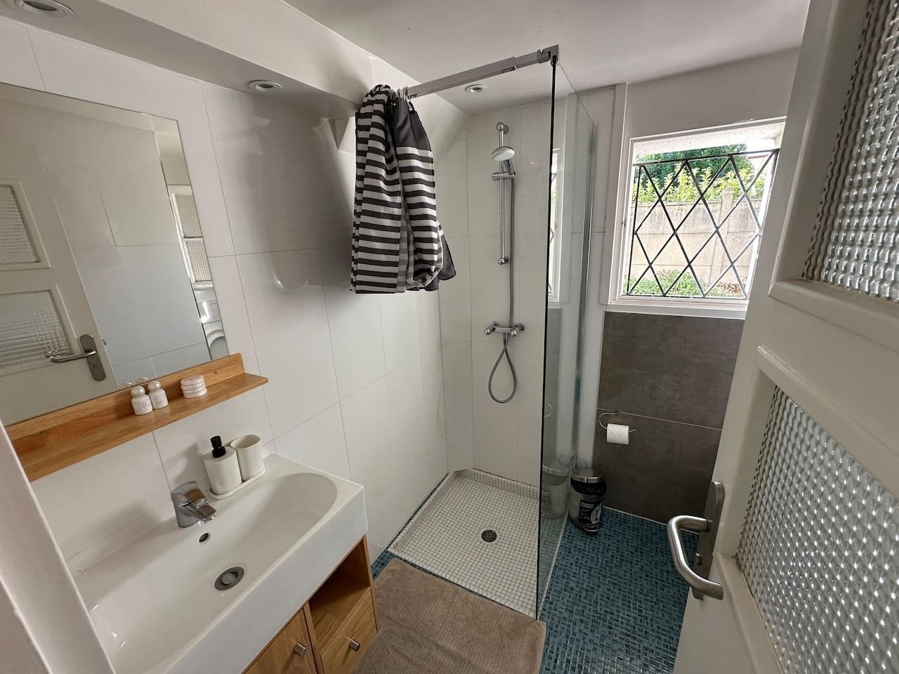 A modern bathroom with a shower, a sink, and a mirror.