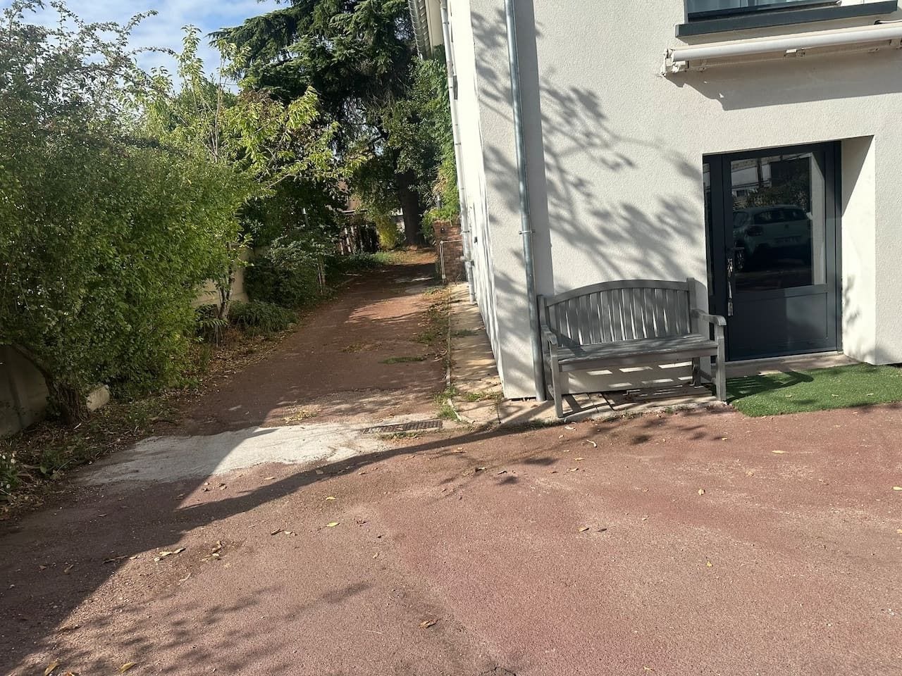 Een geplaveid pad naar een gebouw met een bank.