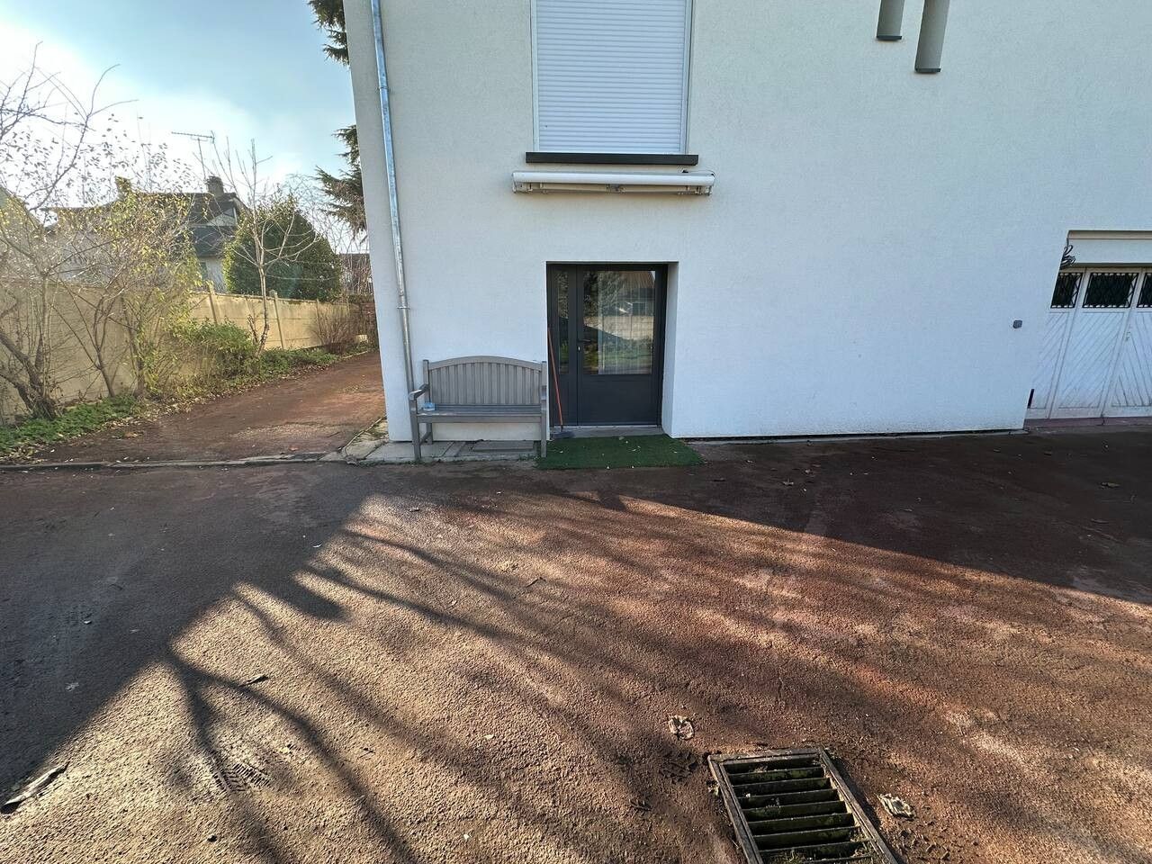 A residential building with a front door, a small porch, and a driveway leading to a garage.