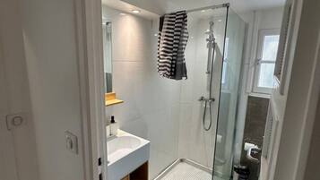 Un bagno moderno con cabina doccia in vetro, lavandino bianco e pavimento a motivi blu.