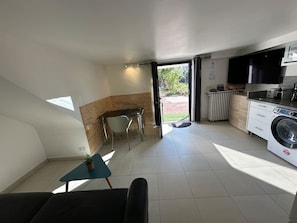 Una cucina moderna con lavatrice integrata, zona pranzo con tavolo e sedie, e vista attraverso una porta aperta.