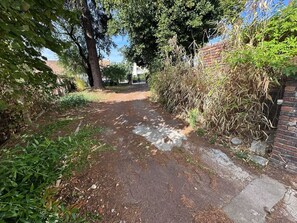 Un vialetto che si snoda attraverso un giardino, con un muro in mattoni su un lato e un sentiero alberato sull'altro.