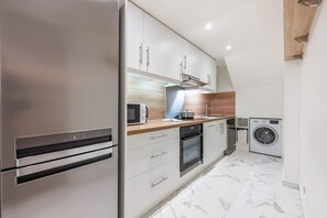 A modern kitchen with stainless steel appliances, wooden countertops, and a built-in washing machine. - 20 min from Paris - 2 parking spaces - 6 beds - 3 bedrooms - 2 bathrooms (Argenteuil)