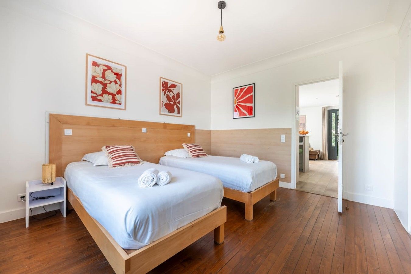 Ein Hotelzimmer mit zwei Betten, Holz-Kopfteilen und Bildern an den Wänden.