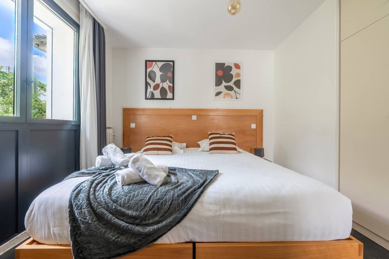 Une chambre d’hôtel avec un grand lit, deux oreillers, une couverture et une tête de lit.