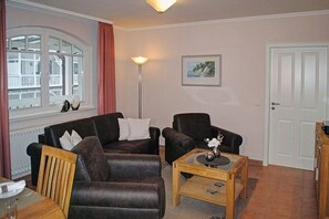 Ein Wohnzimmer mit einer Sofagarnitur, einem Couchtisch, einer Lampe und einer Tür.