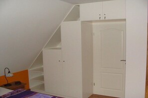 A bedroom with a sloped ceiling, a bed, a wardrobe, and a door. - Holiday home with 3 bedrooms (Seebad Zempin)