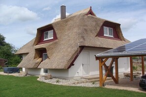A house with a thatched roof, a white exterior, and a solar panel on the right. - Holiday home with 3 bedrooms (Seebad Zempin)
