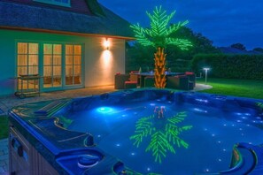A hot tub with a tree-shaped light installation, a covered patio area, and a house in the background. - Holiday home with 3 bedrooms (Seebad Zempin)