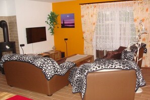 A living room with two sofas, a TV, a fireplace, and a window with curtains. - Holiday home with 3 bedrooms (Seebad Zempin)